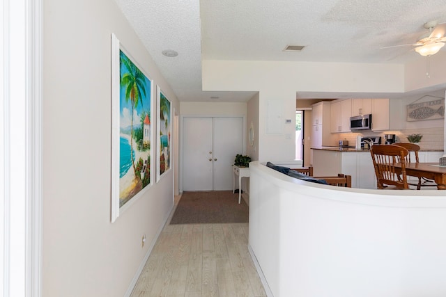 hallway featuring light hardwood / wood-style flooring and a textured ceiling