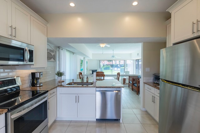 kitchen featuring ceiling fan, appliances with stainless steel finishes, sink, light tile floors, and dark stone counters