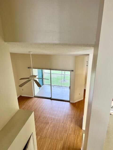 interior space featuring light wood-type flooring, a textured ceiling, and ceiling fan