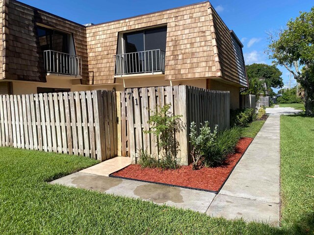 view of side of property featuring a lawn and a balcony