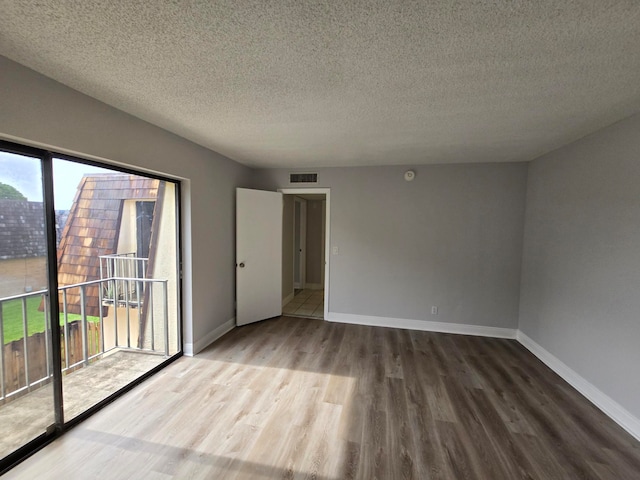 empty room featuring a textured ceiling and wood-type flooring