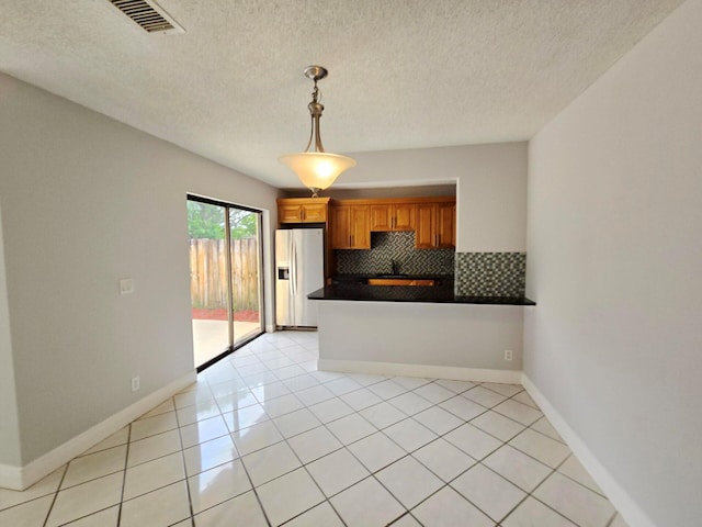 kitchen with light tile patterned floors, kitchen peninsula, decorative light fixtures, backsplash, and stainless steel fridge with ice dispenser