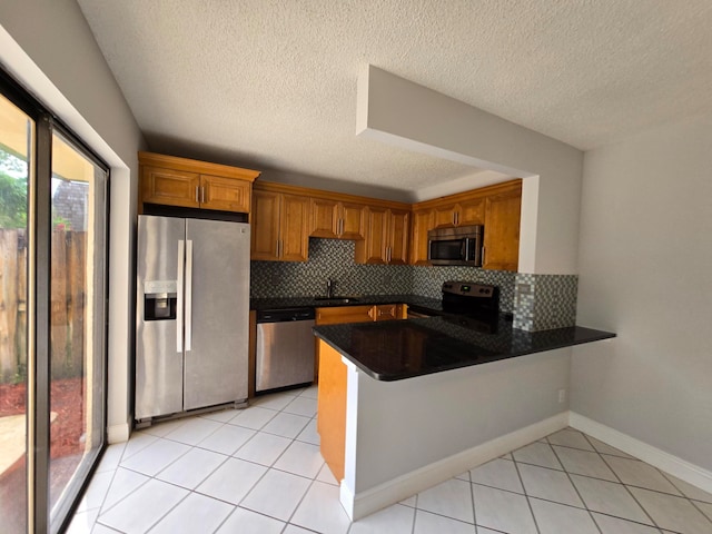 kitchen with appliances with stainless steel finishes, decorative backsplash, a textured ceiling, and kitchen peninsula