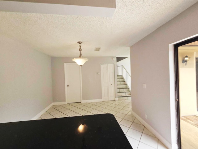 foyer entrance with a textured ceiling and light tile patterned floors