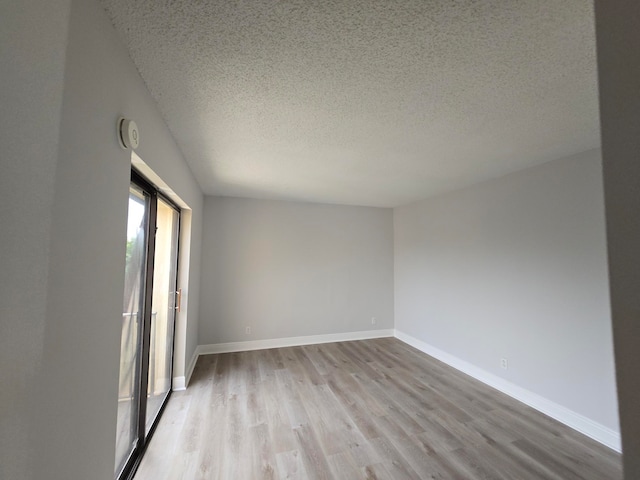 empty room with light hardwood / wood-style floors and a textured ceiling