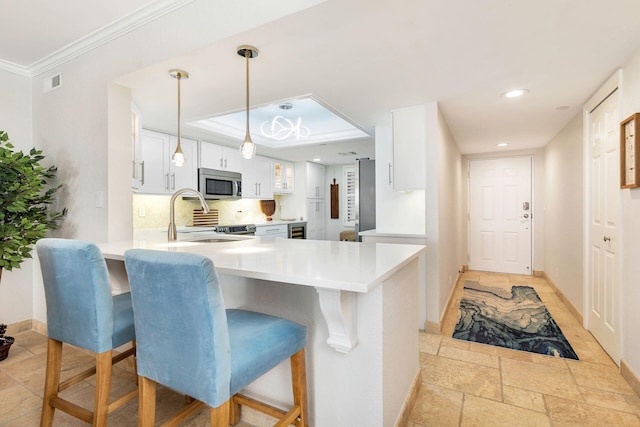 kitchen with white cabinets, pendant lighting, kitchen peninsula, and a breakfast bar area