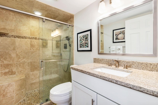 bathroom with vanity, a shower with shower door, and toilet