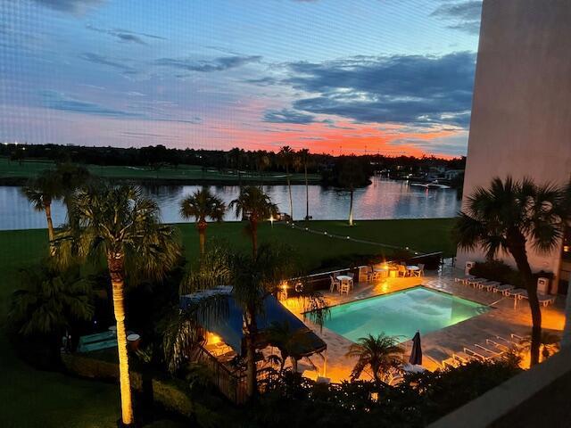 pool at dusk featuring a patio area and a water view