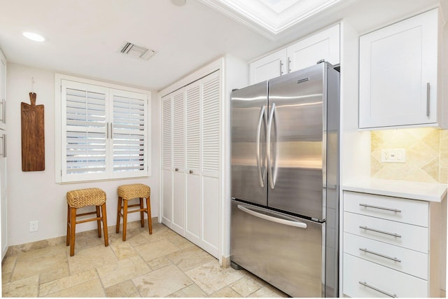 kitchen with stainless steel fridge, tasteful backsplash, white cabinetry, and crown molding