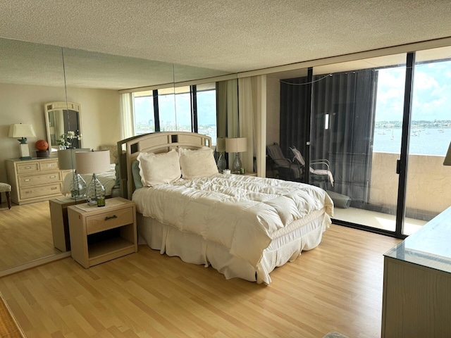 5200 N Flagler Dr Unit 803, West Palm Beach, FL 33407 - bedroom featuring access to exterior, light wood-style flooring, floor to ceiling windows, and a textured ceiling