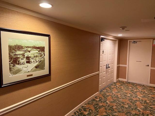 hallway with ornamental molding and dark colored carpet