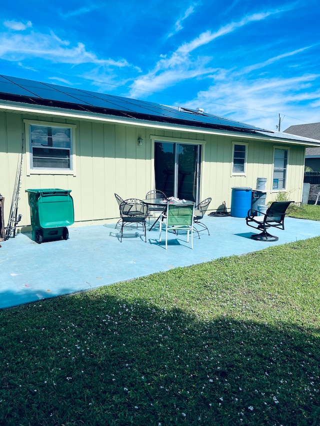 rear view of property with a yard, a patio area, and solar panels