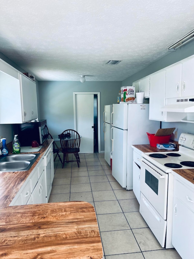 kitchen featuring white appliances, sink, light tile floors, white cabinets, and custom range hood