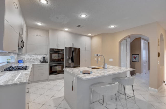 kitchen with light tile floors, tasteful backsplash, appliances with stainless steel finishes, white cabinets, and sink