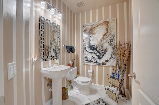 bathroom featuring toilet, sink, and tile flooring