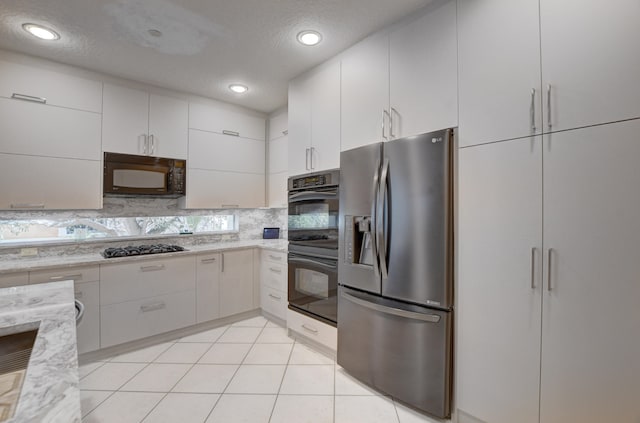 kitchen with white cabinetry, black appliances, light tile flooring, light stone counters, and tasteful backsplash