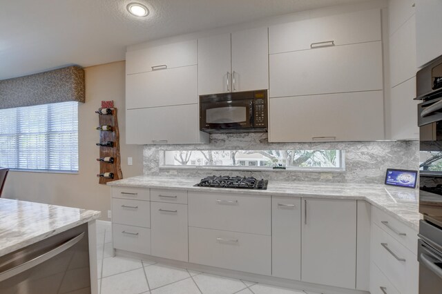 kitchen with white cabinetry, backsplash, black appliances, and light tile flooring