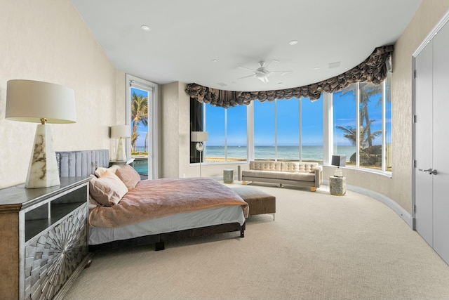 carpeted bedroom featuring multiple windows, a water view, and ceiling fan