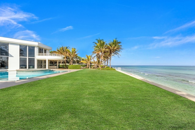 view of yard with a water view, a balcony, and a view of the beach