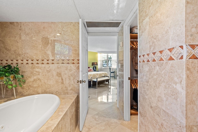 bathroom featuring tile walls, a relaxing tiled bath, tile flooring, and a textured ceiling