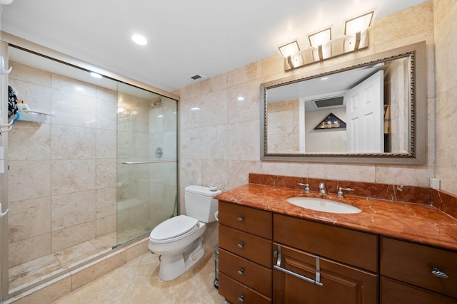 bathroom with tile walls, a shower with door, toilet, and vanity