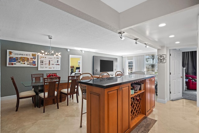 kitchen with hanging light fixtures, light tile flooring, an inviting chandelier, a kitchen bar, and rail lighting