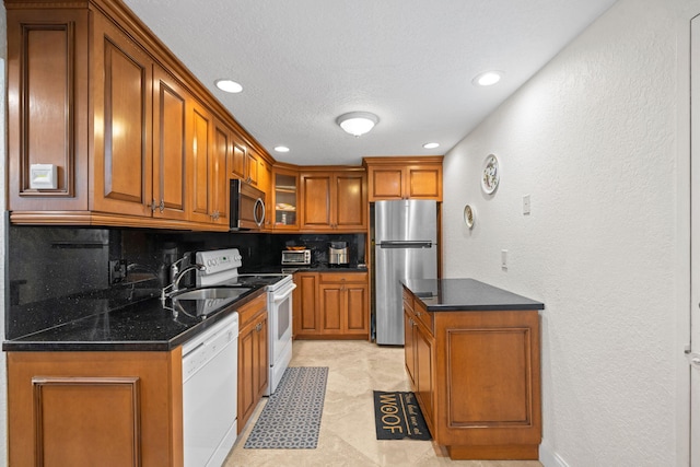 kitchen with light tile flooring, tasteful backsplash, appliances with stainless steel finishes, dark stone countertops, and sink