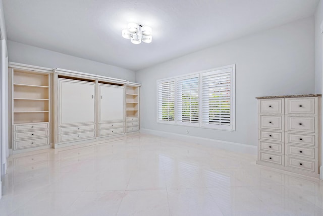 unfurnished bedroom with light tile floors and an inviting chandelier