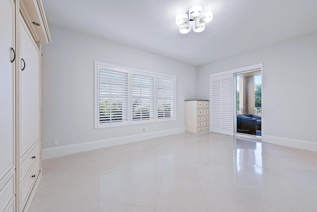 empty room with a notable chandelier and light tile flooring