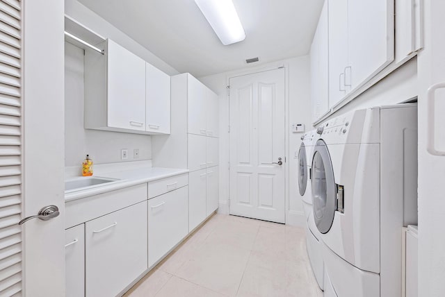 laundry area with cabinets, separate washer and dryer, sink, and light tile floors