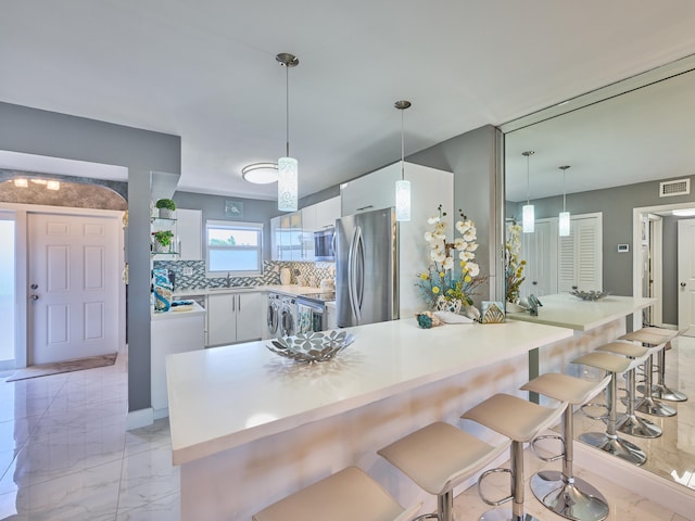 kitchen with white cabinets, sink, backsplash, hanging light fixtures, and stainless steel appliances