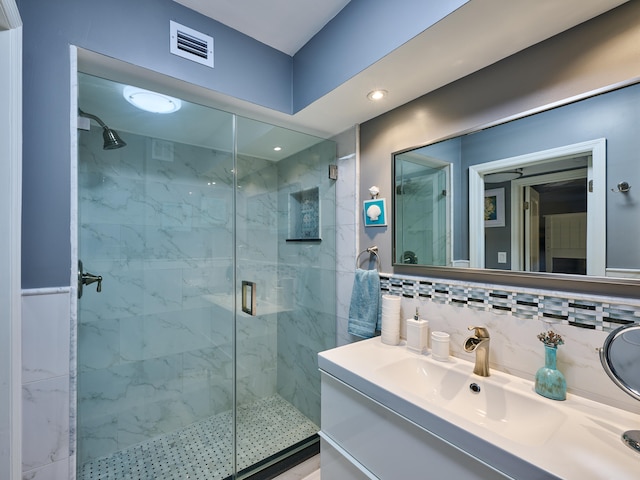 bathroom featuring backsplash, a shower with door, and vanity