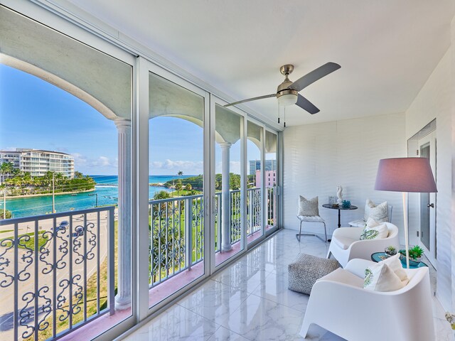 sunroom / solarium with ceiling fan and a water view