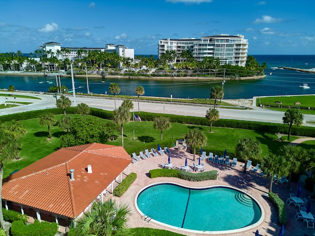 view of pool with a water view and a lawn