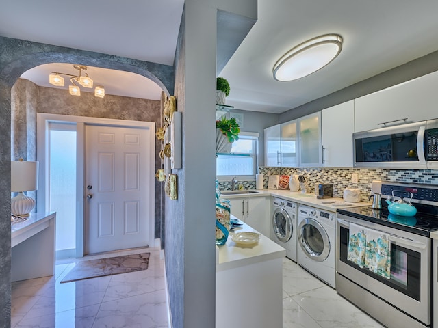 clothes washing area featuring sink, independent washer and dryer, and light tile floors