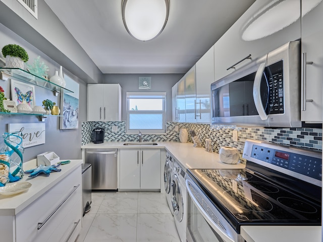 kitchen with washing machine and clothes dryer, sink, backsplash, light tile flooring, and stainless steel appliances