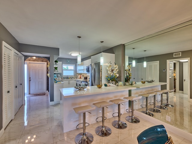 kitchen with decorative light fixtures, appliances with stainless steel finishes, kitchen peninsula, and a breakfast bar area