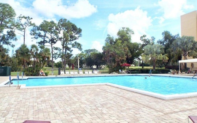 pool with a patio area and fence