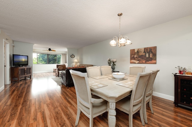 dining room with dark wood-type flooring, ceiling fan with notable chandelier, and a textured ceiling