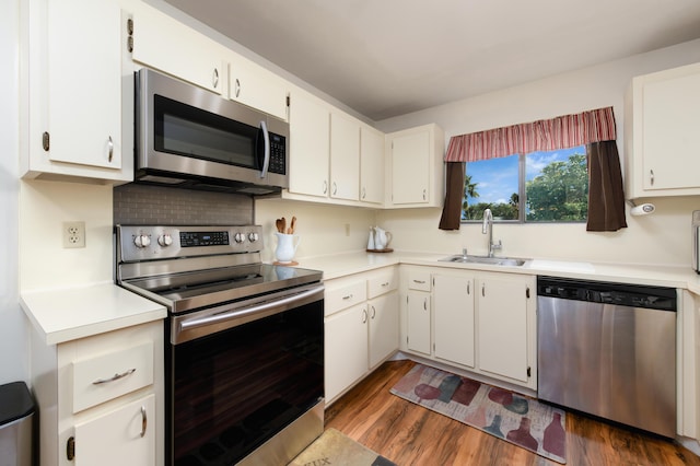 kitchen with a sink, dark wood-type flooring, white cabinets, light countertops, and appliances with stainless steel finishes