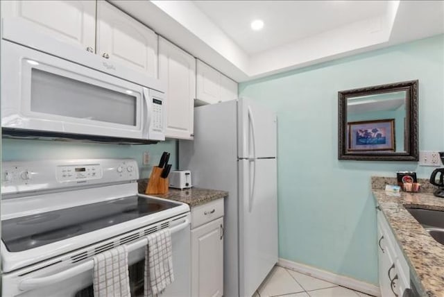 kitchen featuring white appliances, light tile flooring, white cabinets, and light stone countertops