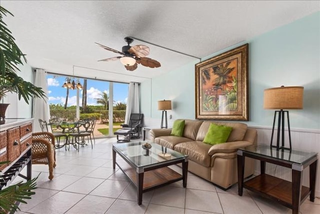 living room featuring light tile floors, a textured ceiling, and ceiling fan with notable chandelier