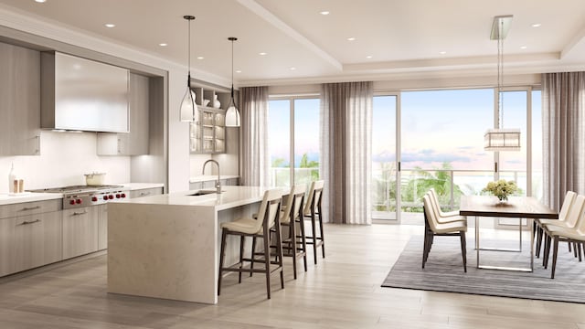 kitchen with a kitchen island with sink, light hardwood / wood-style flooring, stainless steel gas stovetop, sink, and hanging light fixtures