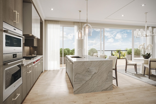 kitchen with an inviting chandelier, decorative light fixtures, a center island with sink, light hardwood / wood-style floors, and sink