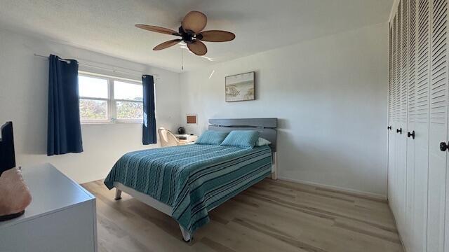 bedroom with ceiling fan, light hardwood / wood-style floors, and a closet