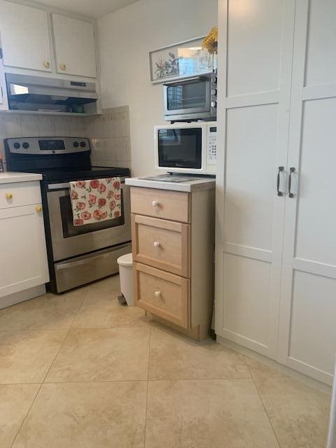 kitchen featuring backsplash, light brown cabinets, stainless steel range with electric cooktop, and light tile patterned flooring