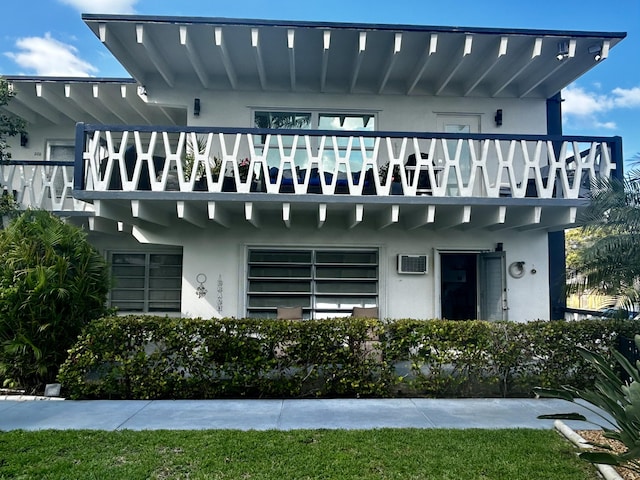 back of property featuring a balcony and stucco siding