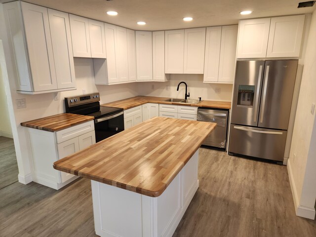 kitchen featuring white cabinetry, appliances with stainless steel finishes, sink, hardwood / wood-style flooring, and butcher block counters