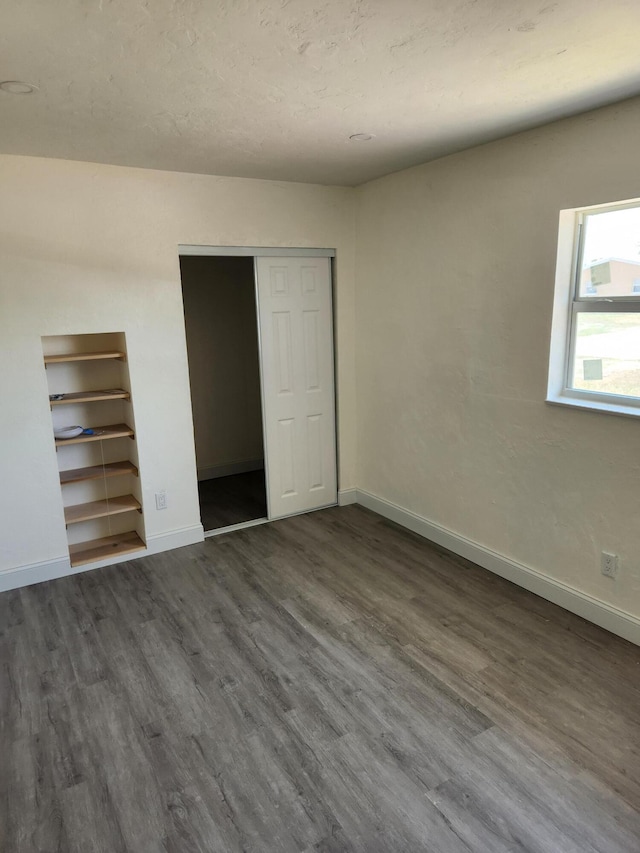 unfurnished bedroom featuring a closet and dark wood-type flooring