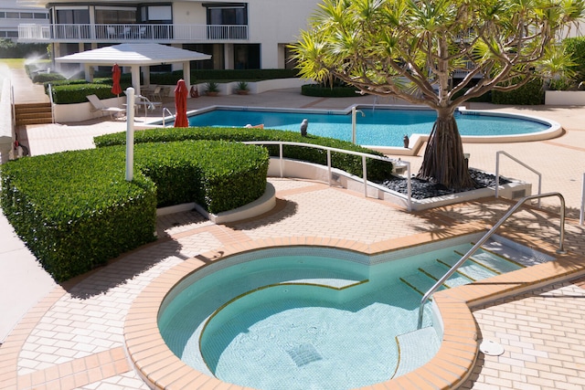 view of pool featuring a patio and a hot tub